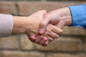 A close-up of a firm handshake between two people against a blurred brick background, symbolizing trust, partnership, and professional integrity.